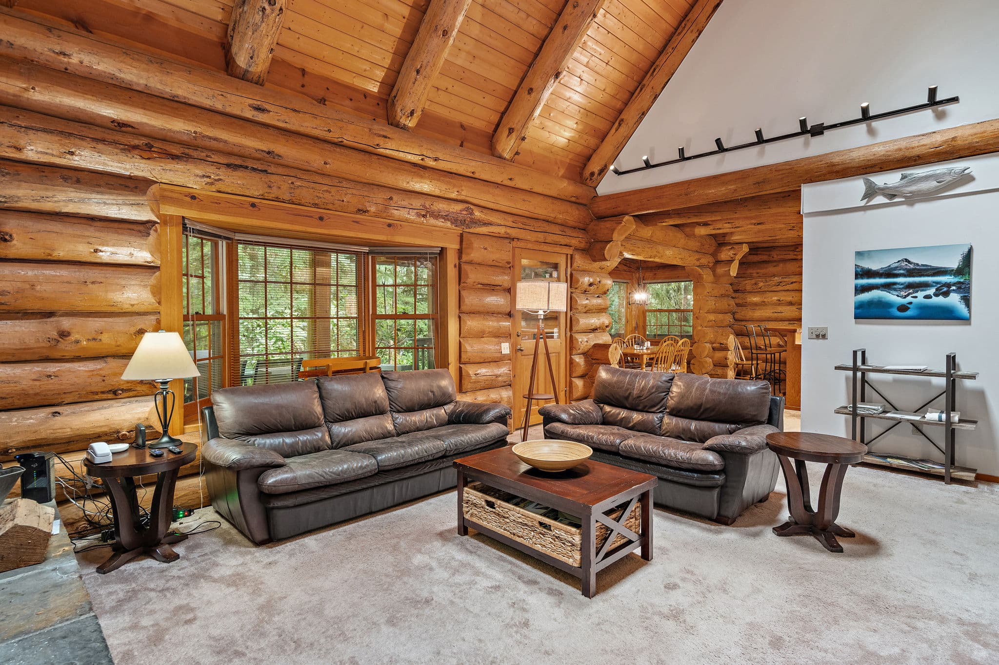 Leather seating around the fireplace with a bay window to the forest.