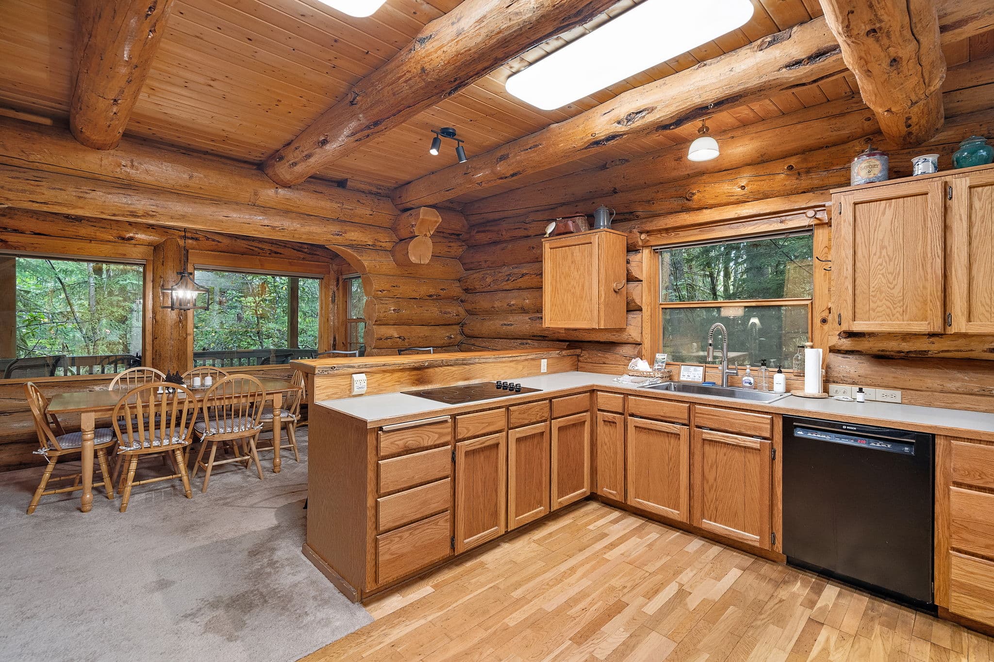 Cooktop, sink, and dishwasher with hardwood underfoot.