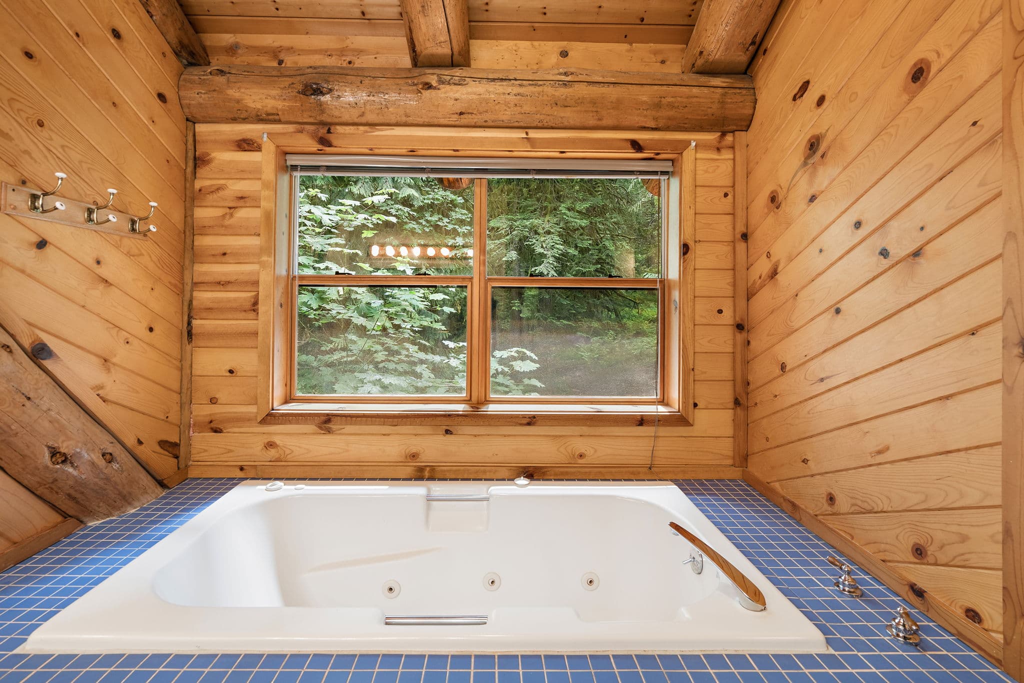 Jetted soaking tub set beneath a forest window.
